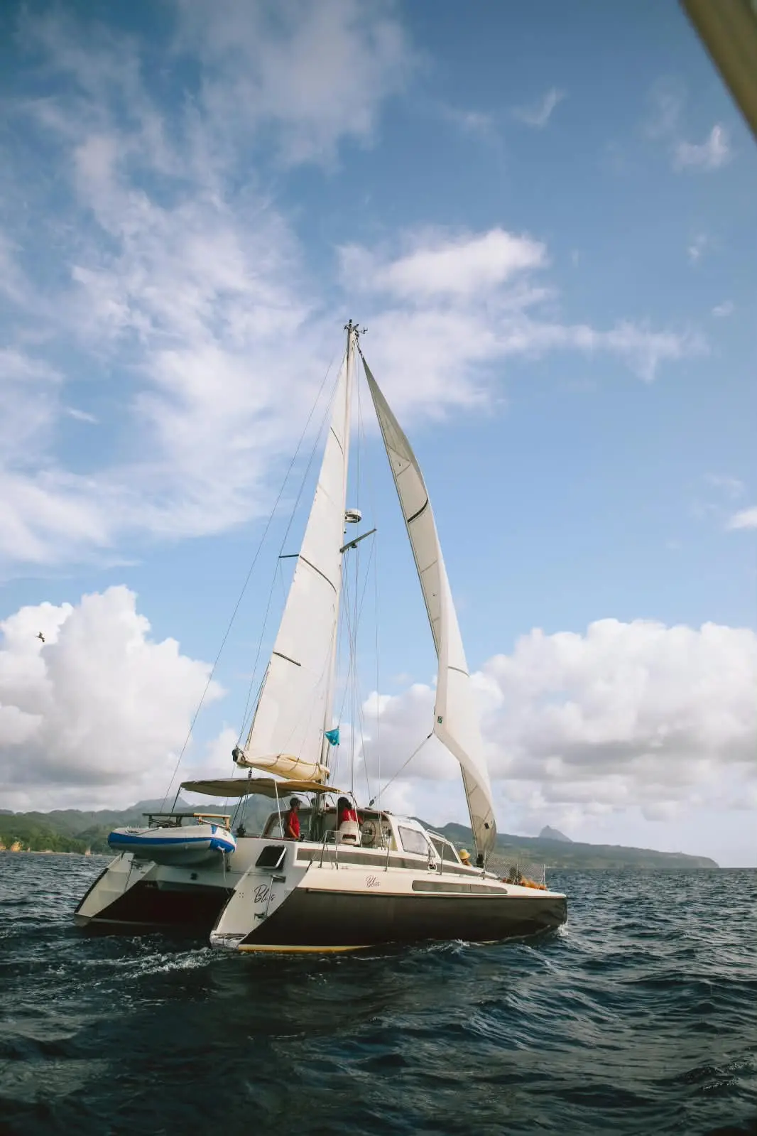 Bliss under full sail beneath a big sky of white clouds