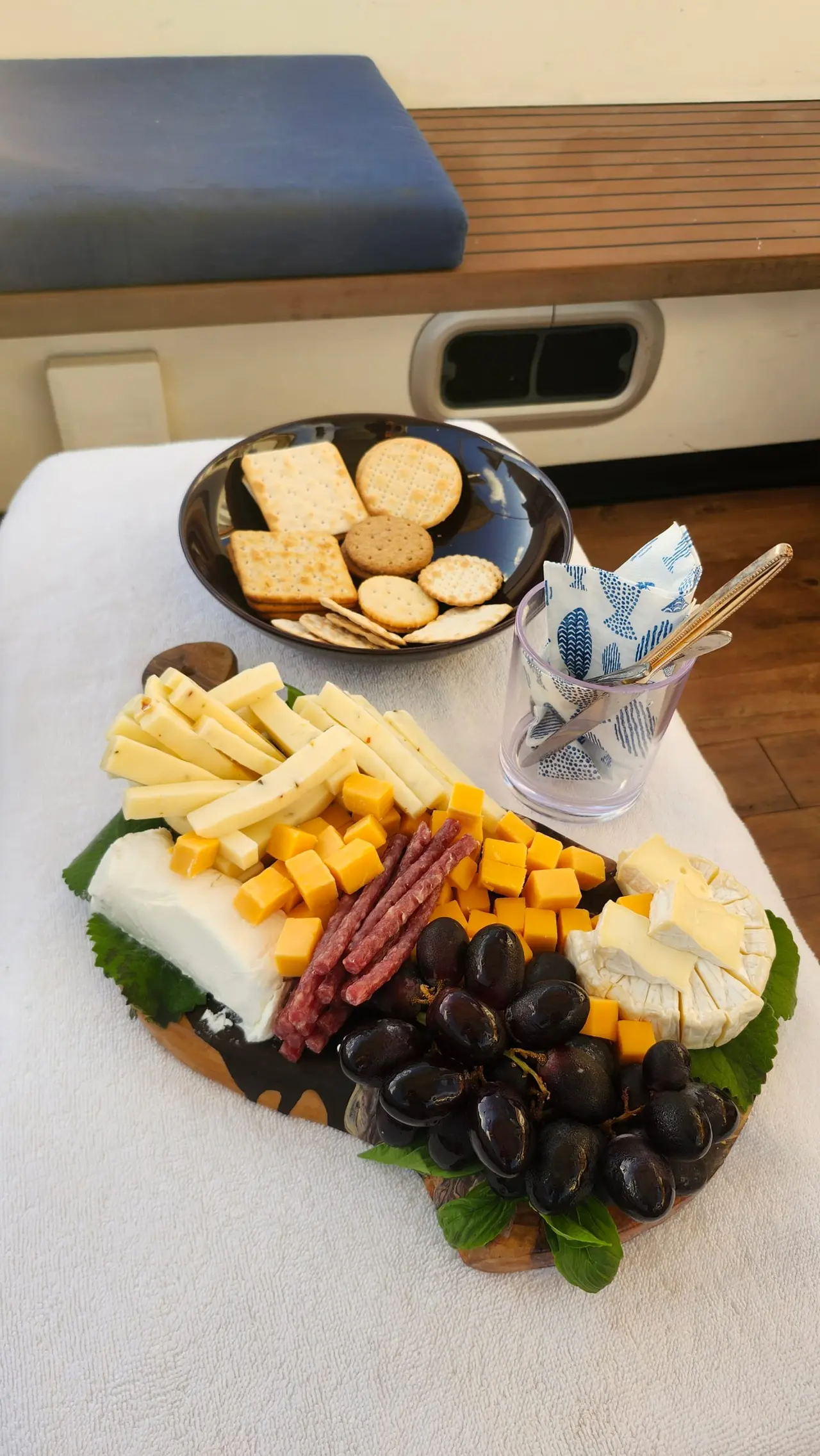 A platter of cheese, crackers, fruit and cured meats served on board
