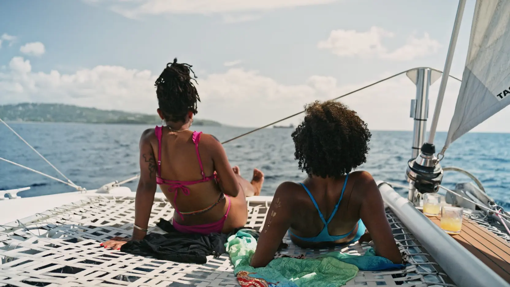 Two guests lounging on the bow trampoline under sail